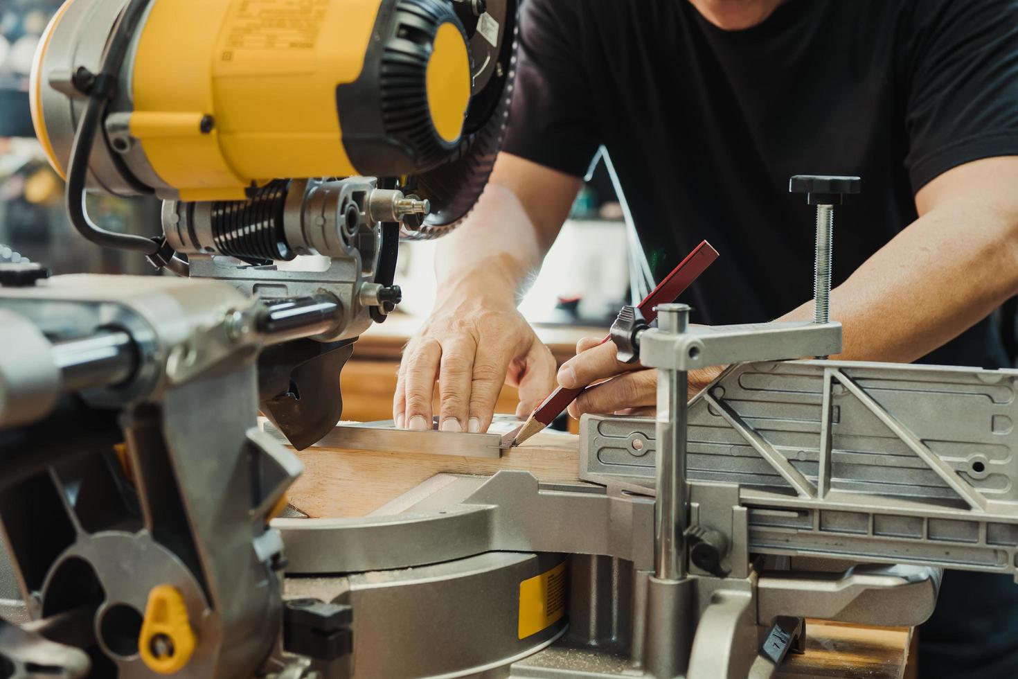 le charpentier utilise un carré de machiniste et un marquage au crayon sur le bois sur la table de scie à onglets à l'atelier, au bricoleur et au concept de menuiserie. mise au point sélective photo