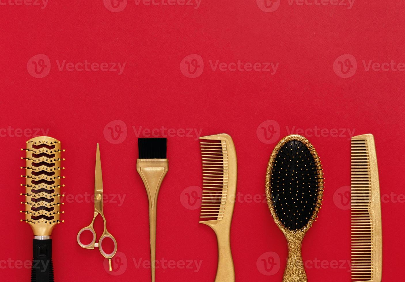 fond avec des outils de coiffure sur le rouge. accessoires de salon de coiffure or, peignes à cheveux, ciseaux. bannière et modèle de conception avec un espace pour le texte. photo