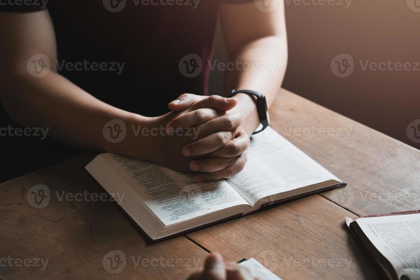un groupe de chrétiens s'assoient ensemble et prient autour d'une table en bois avec des pages bibliques ouvertes floues dans leur classe. prière pour les frères, foi, espoir, amour, réunion de prière photo