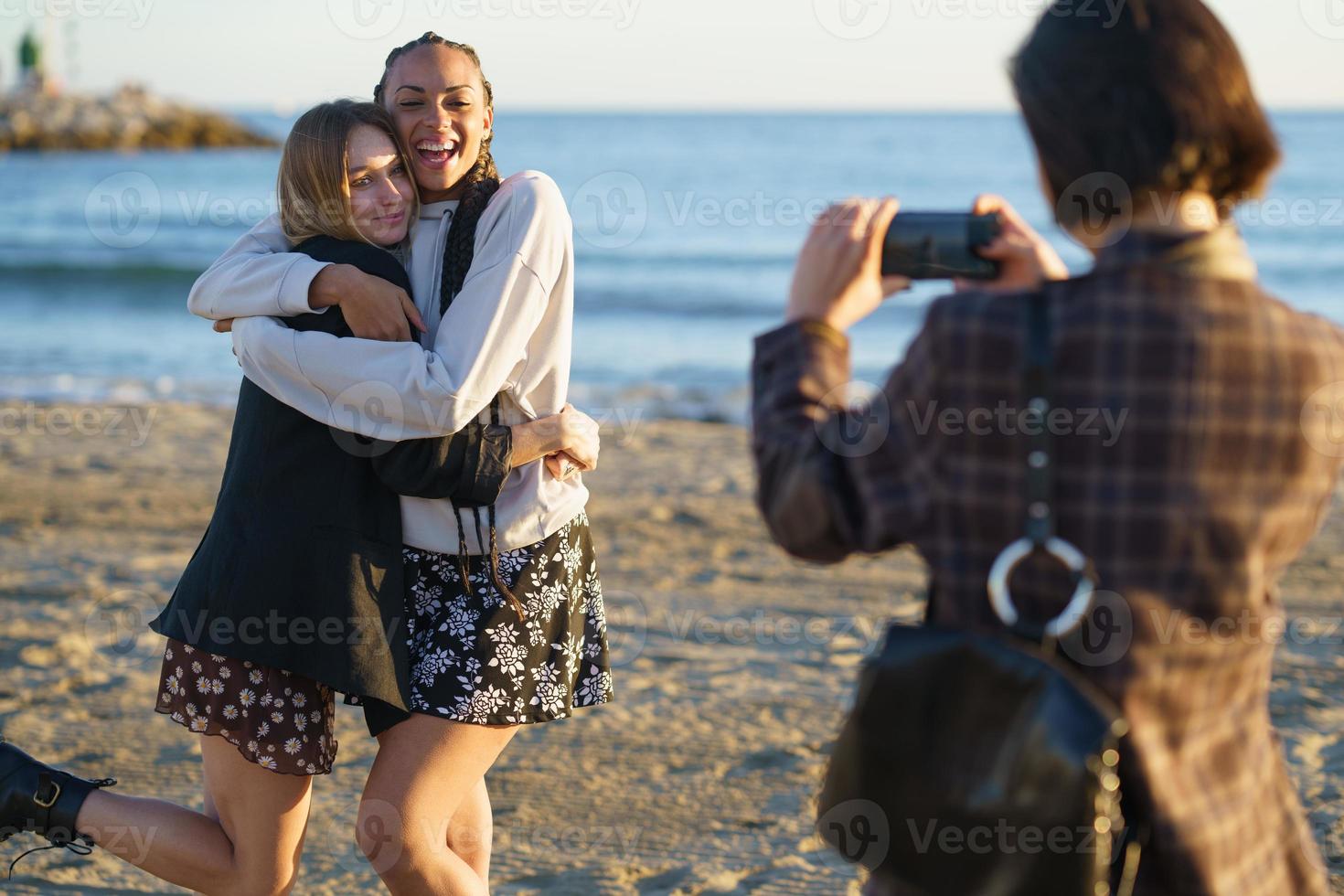 femme sans visage prenant une photo d'étreindre diverses copines au bord de la mer