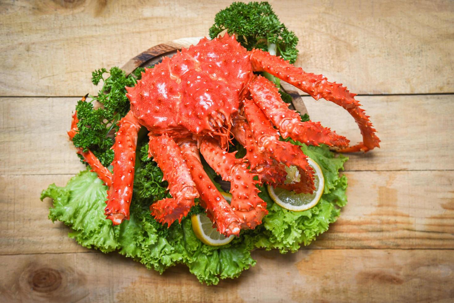 crabe royal d'alaska cuit à la vapeur ou fruits de mer bouillis et légumes salade de laitue avec fond en bois - crabe rouge hokkaido photo