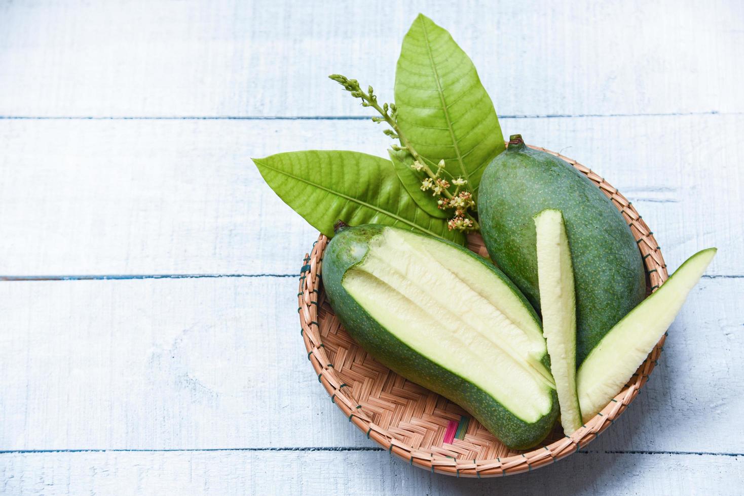 mangue verte fraîche et panier de feuilles vertes - tranche de mangue fruits d'été photo