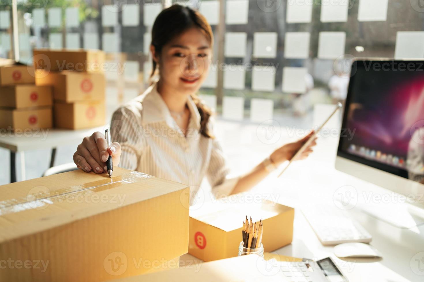 portrait jeune femme séduisante en asie propriétaire entreprise de démarrage regarder le travail de la caméra heureux avec la boîte à la maison préparer la livraison de colis dans la chaîne d'approvisionnement des PME, l'approvisionnement, le concept de commerce en ligne omnicanal. photo