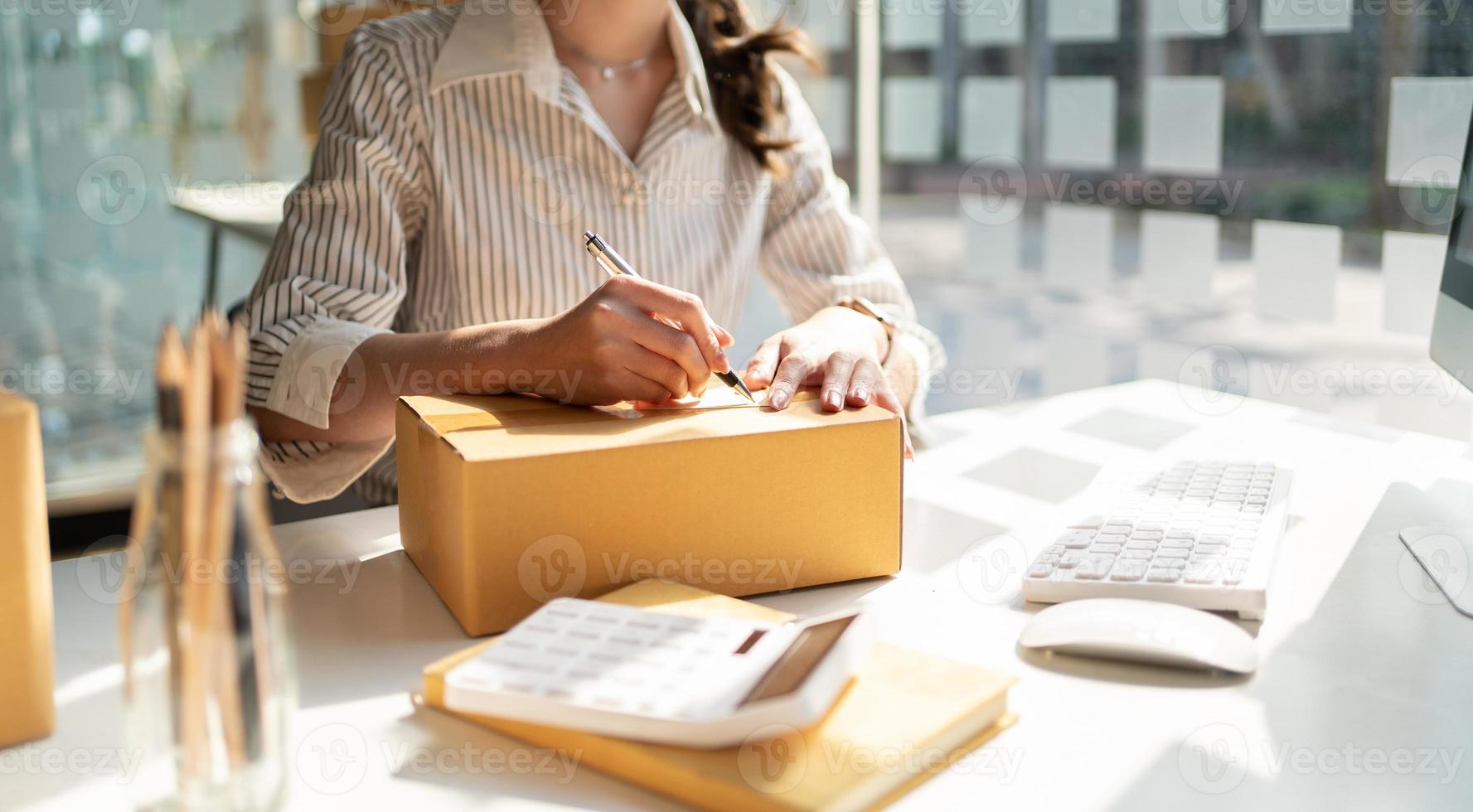 Démarrage de petites entreprises Propriétaires de PME Les femmes entrepreneurs écrivent l'adresse sur la boîte de réception et vérifient les commandes en ligne pour se préparer à emballer les boîtes, vendre aux clients, les idées commerciales des PME en ligne. photo