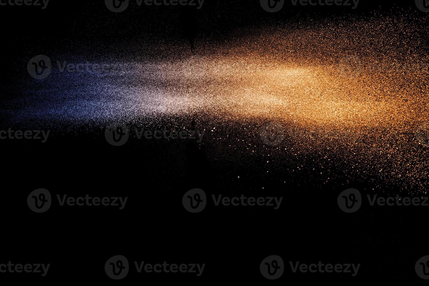 explosion de particules de poussière orange bleu sur fond noir. éclaboussures de poussière de poudre de couleur. photo