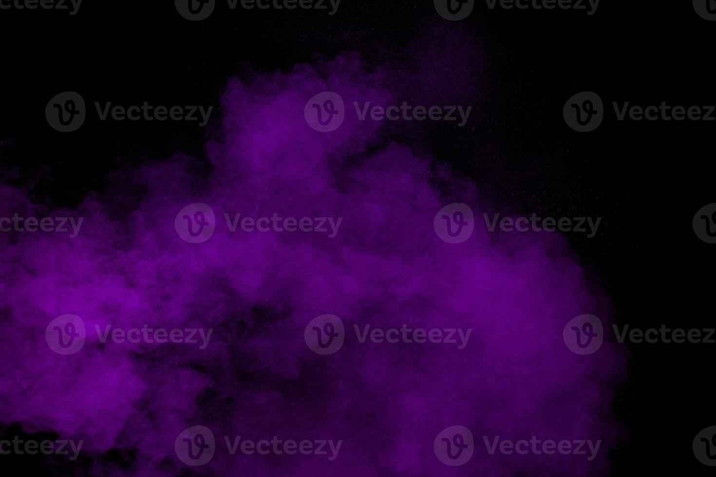 explosion abstraite de poudre violette sur fond noir, mouvement figé d'éclaboussures de poussière violette. photo