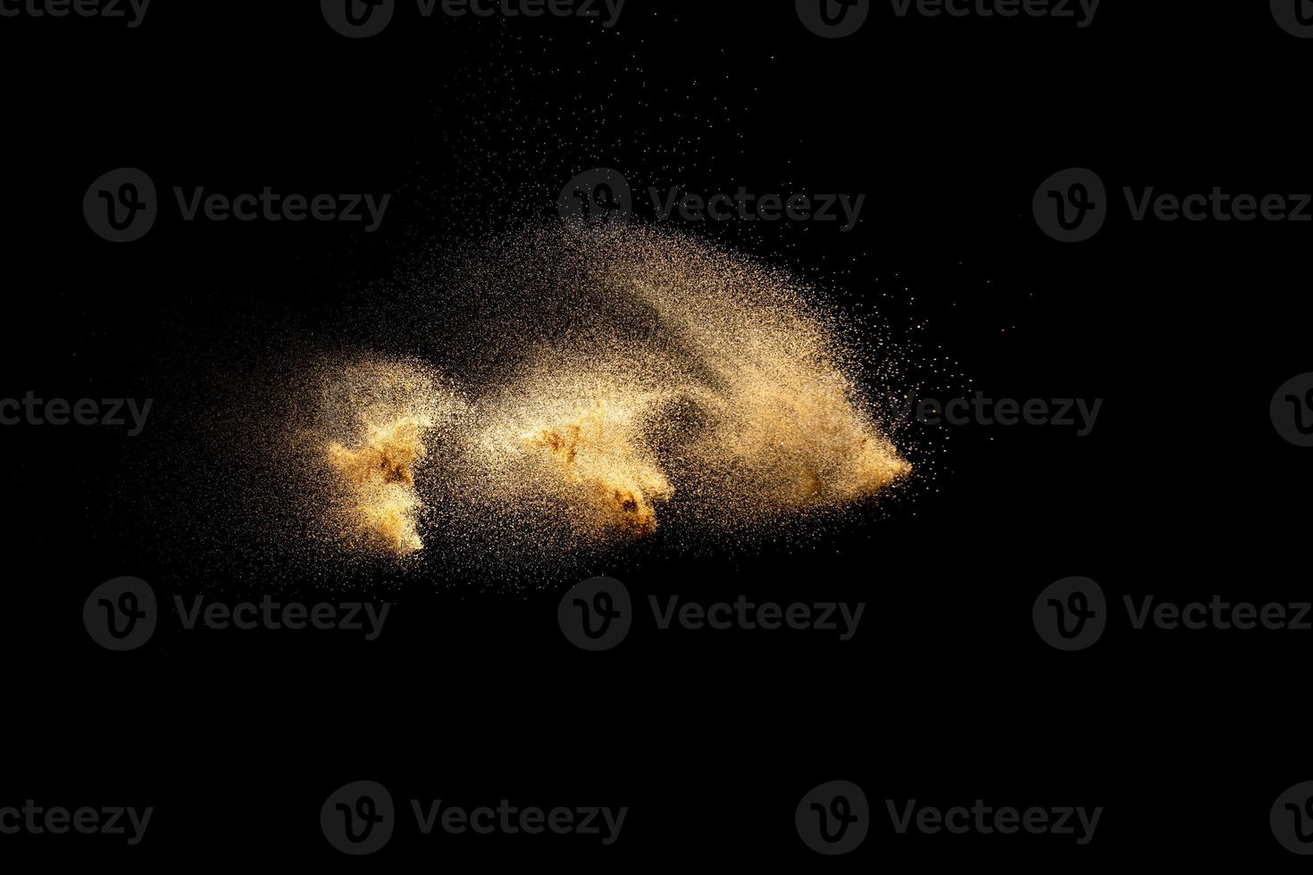 explosion de sable doré isolée sur fond noir. nuage de sable abstrait. éclaboussures de sable de couleur dorée sur fond sombre. vague de mouche de sable jaune dans l'air. photo