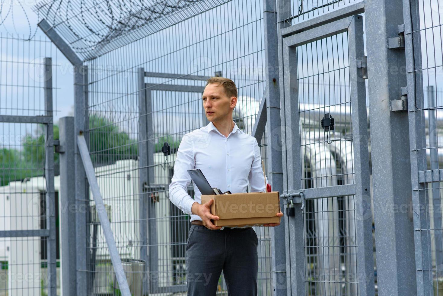 l'homme d'affaires est sorti de prison avec ses affaires et réfléchit à ce qu'il faut faire ensuite. un homme se tient près de la sortie de la prison. photo