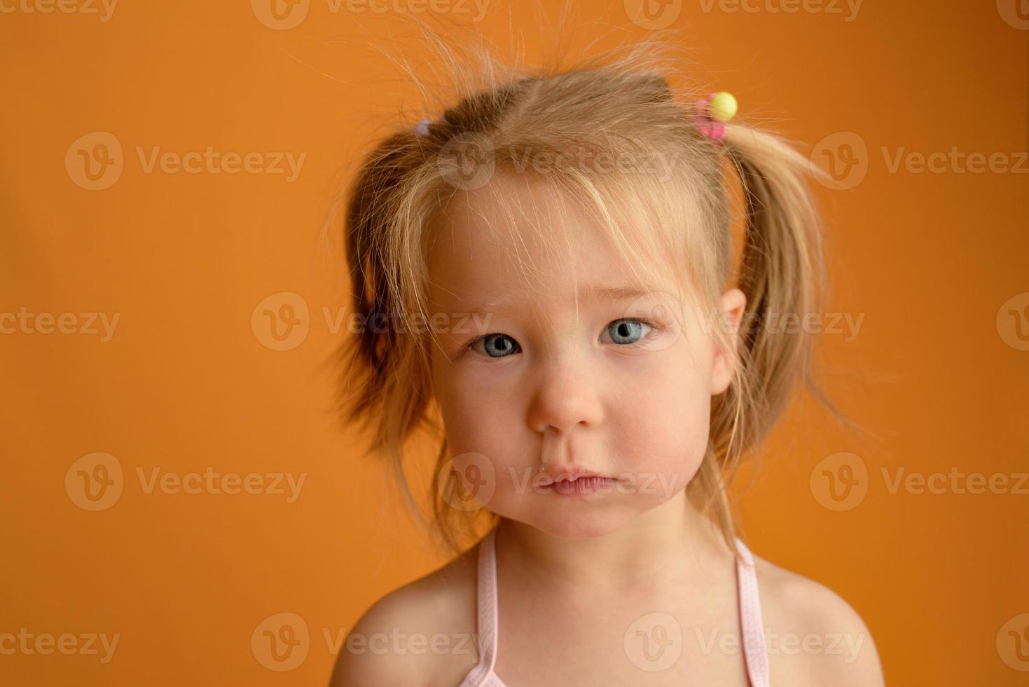 une petite fille vêtue d'un maillot de bain à l'âge d'un an et demi saute ou danse. la fille est très contente. photo prise en studio sur fond jaune.