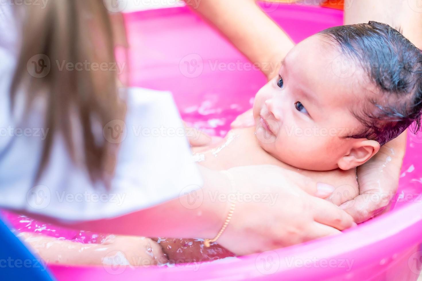 maman asiatique douche bébé pour nettoyer la saleté donner à l'enfant dans  le bain récipient