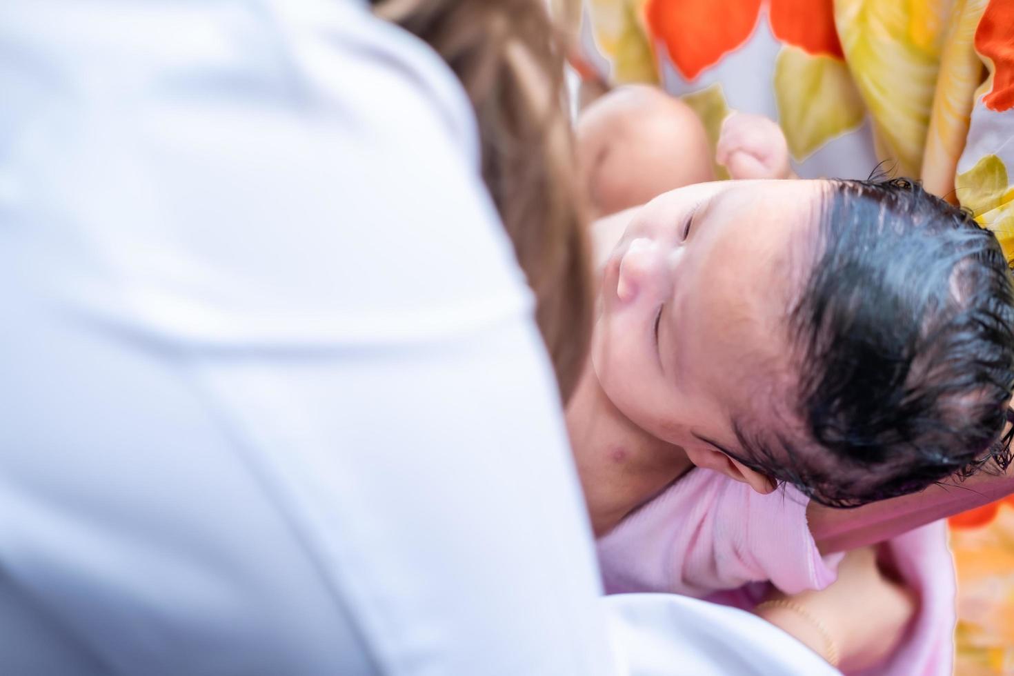 maman asiatique douche bébé pour nettoyer la saleté donner à l'enfant dans le bain récipient pour la propreté mode de vie famille entre mère et enfant utilisé pour la douche de bébé produits crème shampooings lotions et produits de soin pour bébé photo