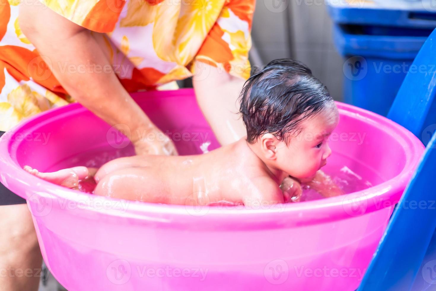 maman asiatique douche bébé pour nettoyer la saleté donner à l'enfant dans  le bain récipient