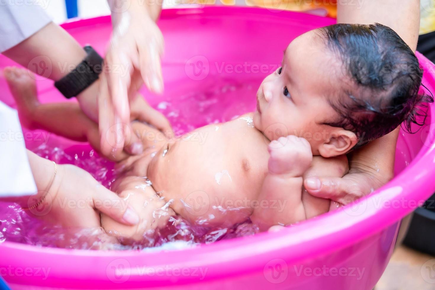 maman asiatique douche bébé pour nettoyer la saleté donner à l'enfant dans  le bain récipient