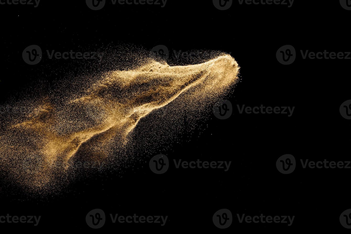 explosion de sable de rivière à sec. éclaboussures de sable de couleur dorée sur fond sombre. photo