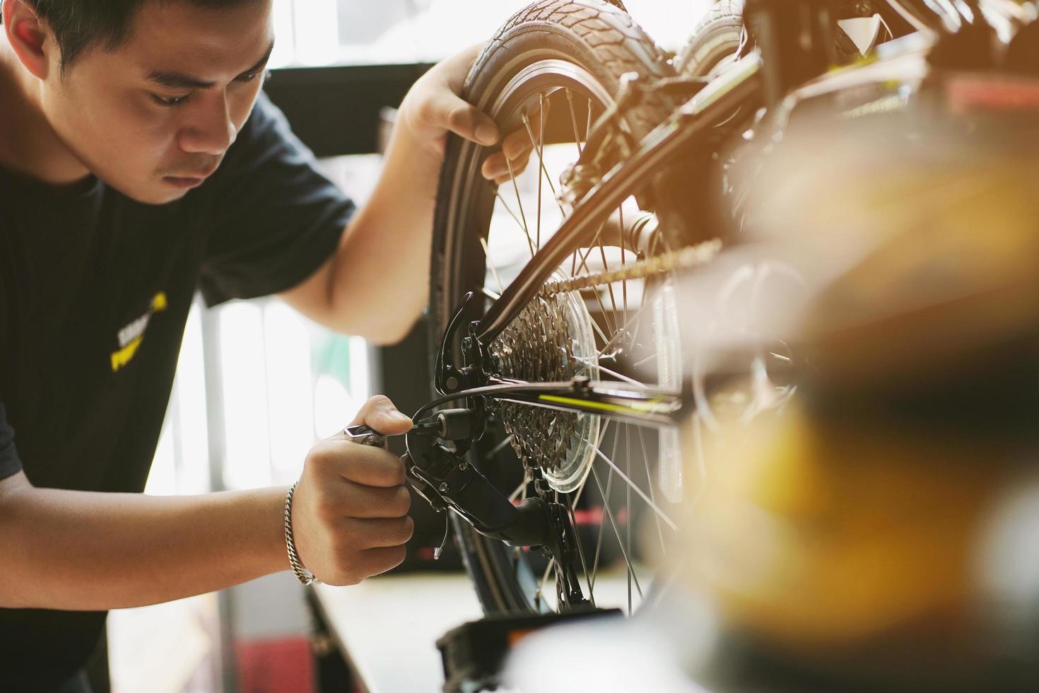 un mécanicien de vélo répare un vélo pliant en atelier. régler le dérailleur arrière, le concept d'entretien et de réparation photo