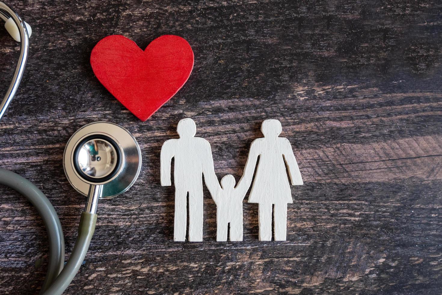 coeur rouge, stéthoscope et famille d'icônes sur un bureau en bois. notion d'assurance médicale photo