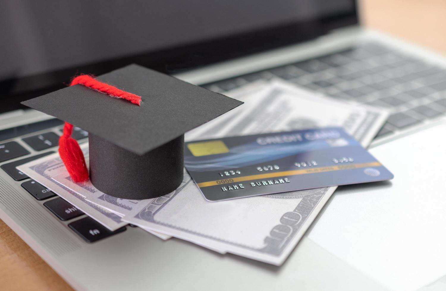 carte de crédit, modèle de chapeau académique et cahier sur un bureau en bois. paiement en ligne à l'aide d'un ordinateur portable photo