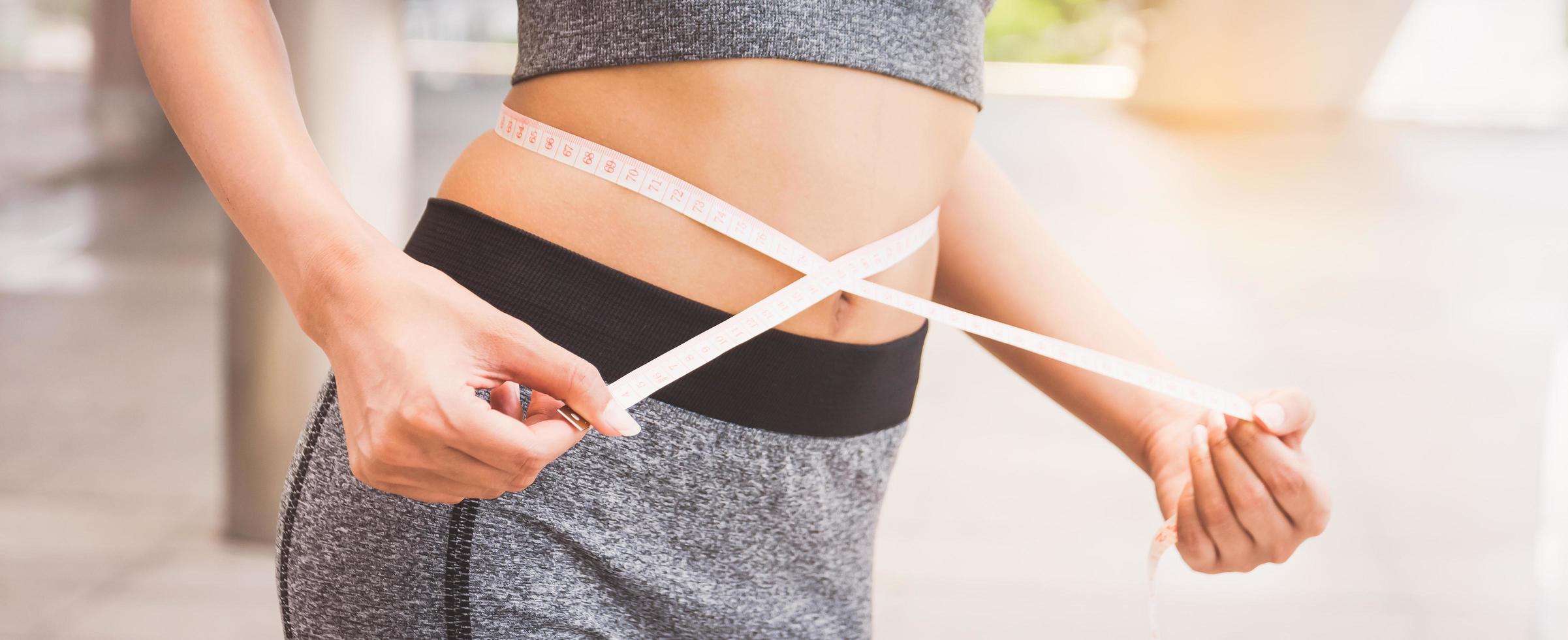 jeune femme mesurant sa taille avec un ruban à mesurer photo