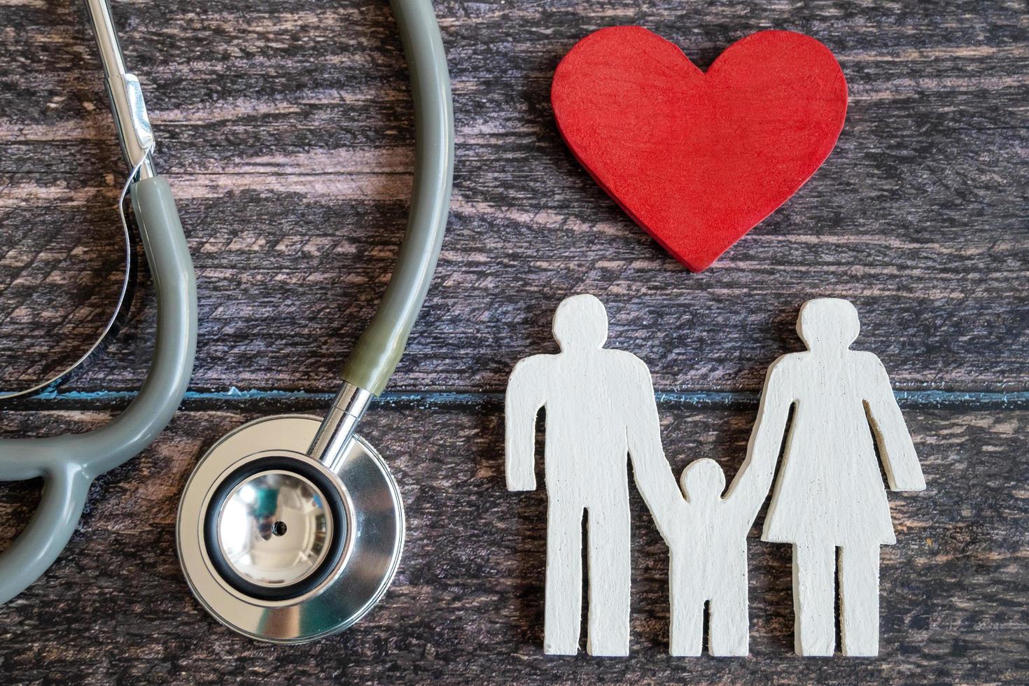 coeur rouge, stéthoscope et famille d'icônes sur un bureau en bois. notion d'assurance médicale photo