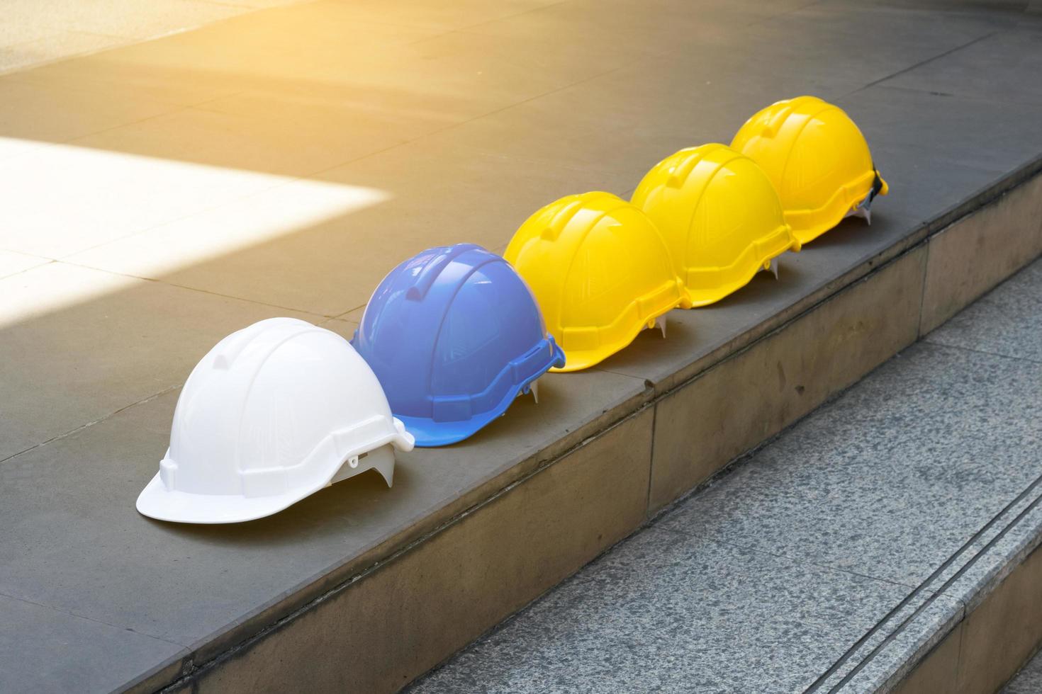 chapeau de casque de sécurité dur blanc jaune et bleu sur sol en béton photo