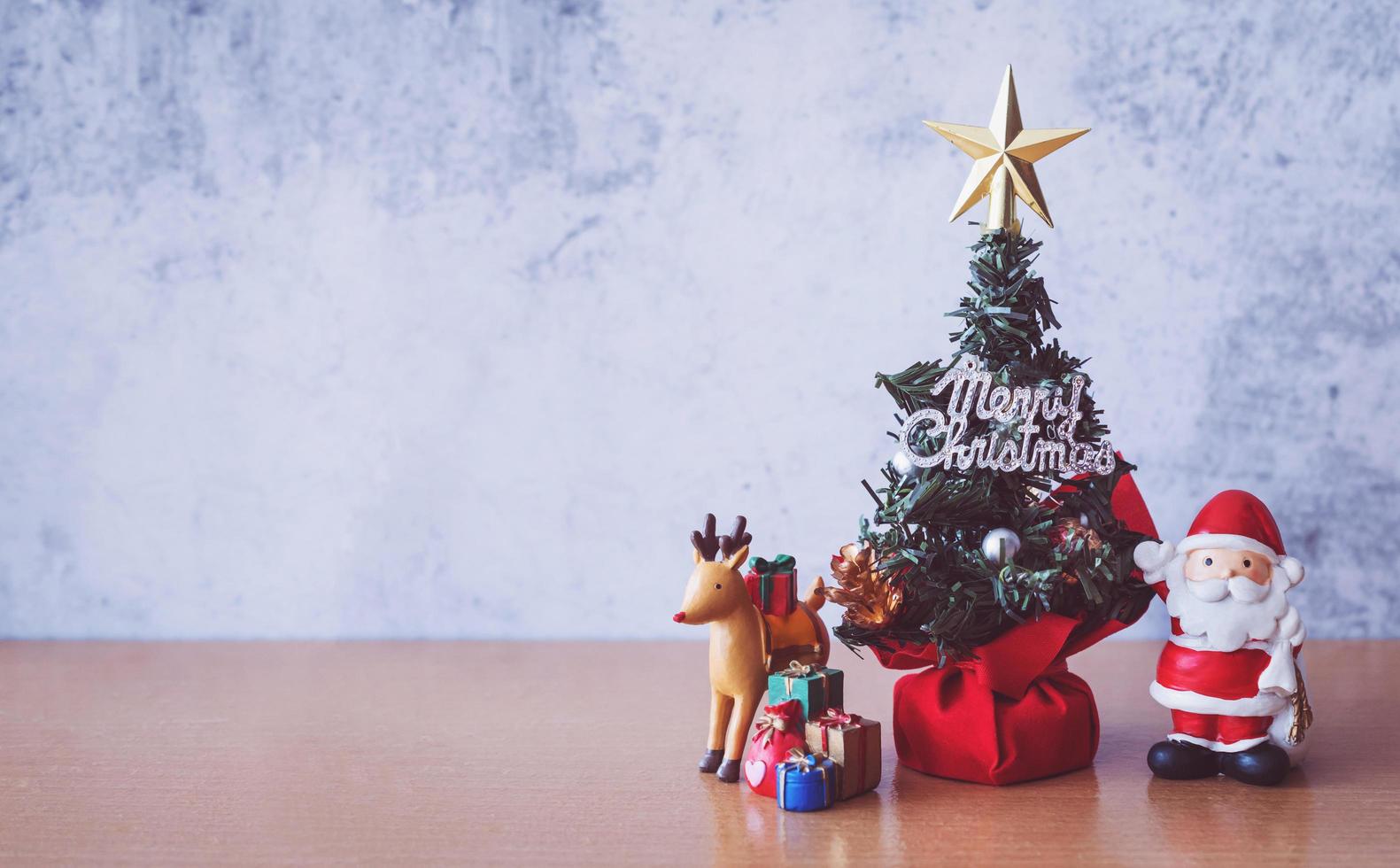 décoration de noël - père noël, arbre et cadeau sur table en bois. concept de noël et bonne année photo