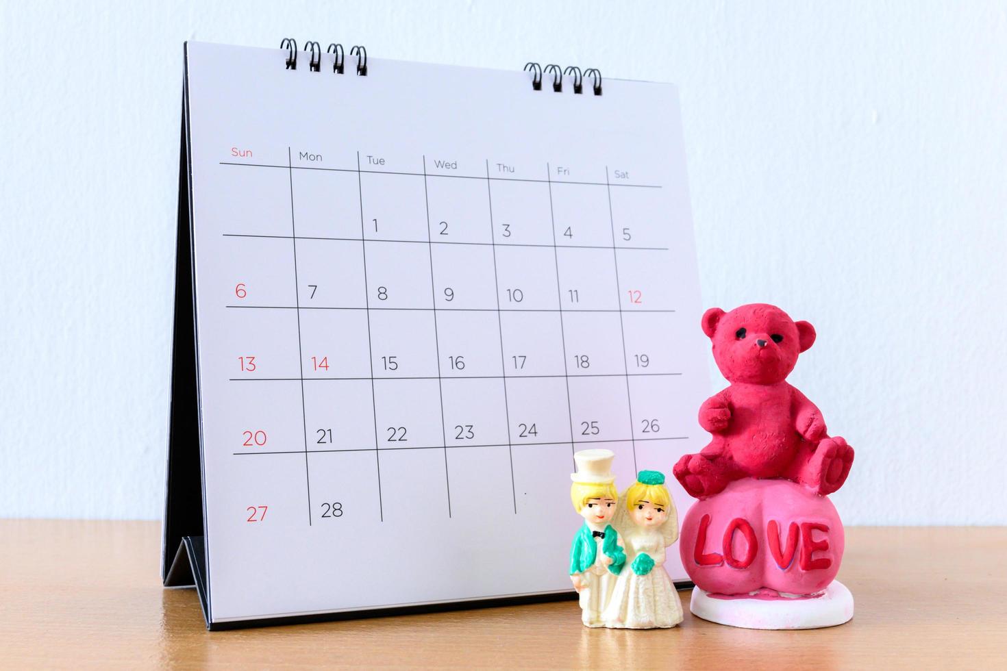 couple marié miniature devant le calendrier. concept pour le mariage saint valentin. photo