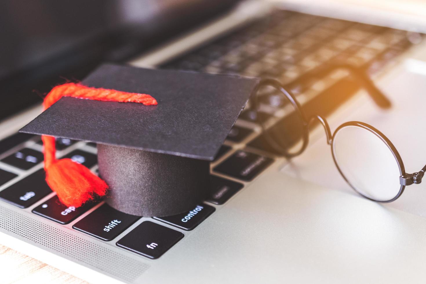 modèle de chapeau de graduation et cahier sur un bureau en bois. photo