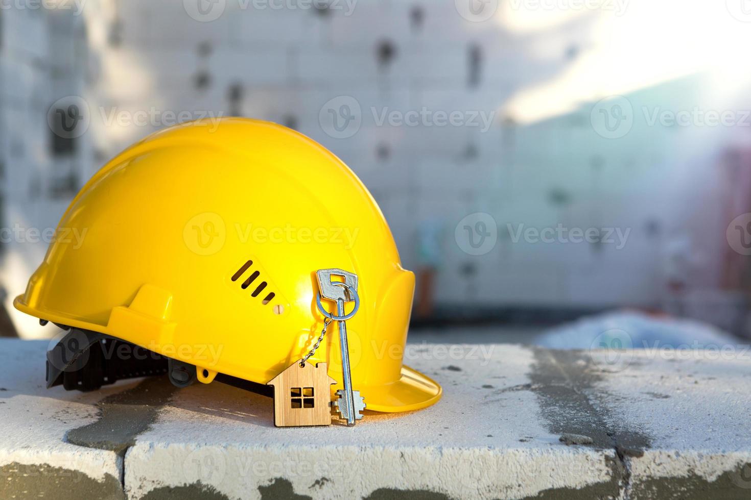 casque jaune de construction et clé de la maison sur la fenêtre du logement en blocs de béton poreux. construction clé en main, future maison, ingénierie, bâtiment. la sécurité du travail. copie espace photo