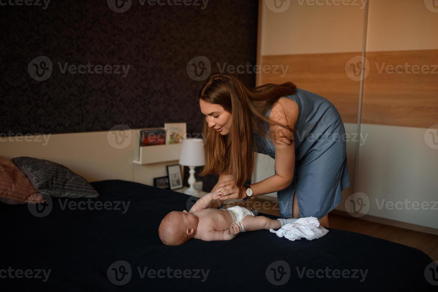 jeune mère change les vêtements de son fils photo