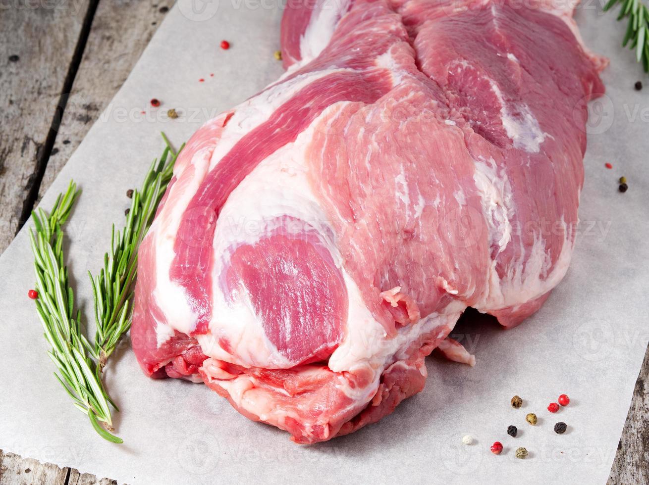 cou de porc frais cru, gros morceau entier sur du papier parchemin blanc, sur une vieille table en bois grise dans la cuisine, vue de dessus photo