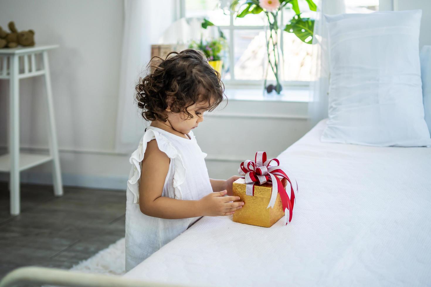 jolie petite fille heureuse après avoir reçu le coffret cadeau au lit de ses parents. en raison de l'anniversaire, joyeuses fêtes. cadeau et cadeau photo