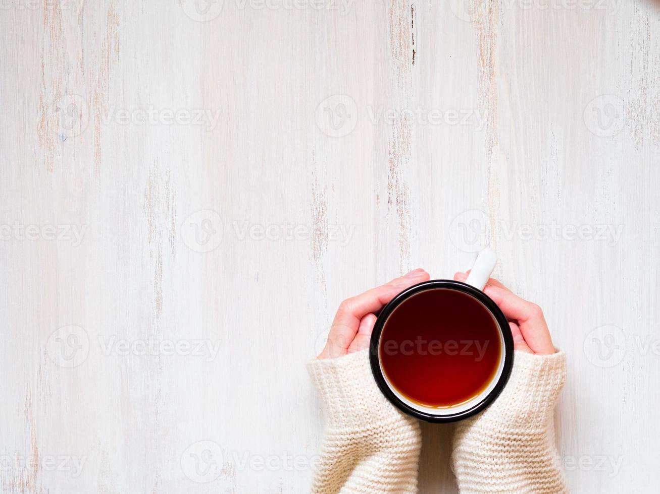 mains féminines tenant une tasse de thé noir chaud. photo