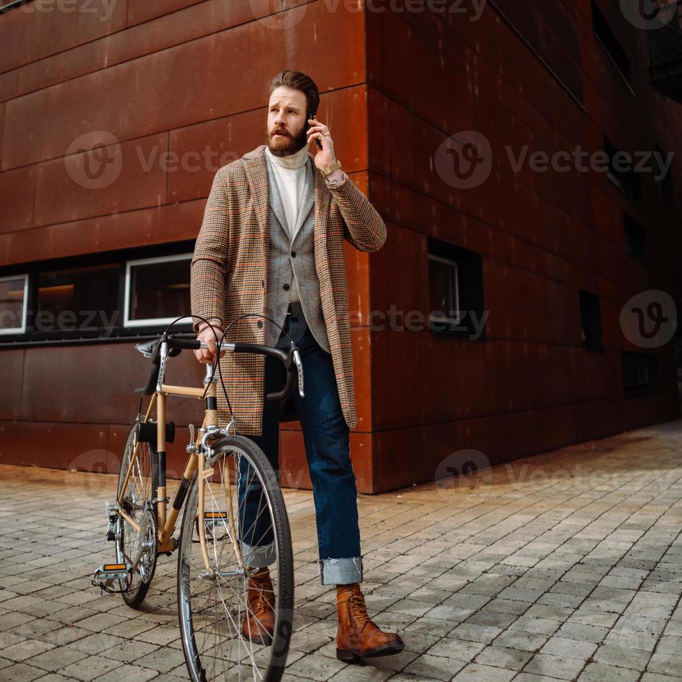 photographie carrée. homme d'affaires tenant un téléphone portable. sur le chemin du travail à vélo photo