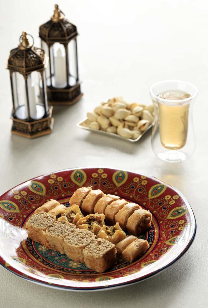 baklava traditionnel turc, arabe, moyen-oriental. vue de dessus. bonbons cuits au four arabes dans une assiette blanche sur une table en bois sombre. mini-baklawa. photo