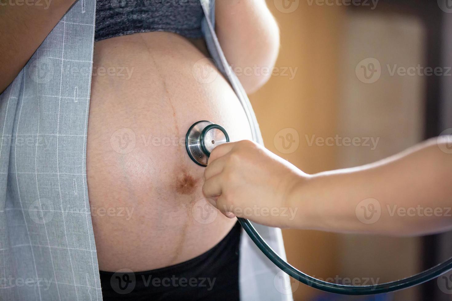 portrait en coupe médiane d'une femme méconnaissable au cours des derniers mois de la grossesse tenant doucement son gros ventre photo