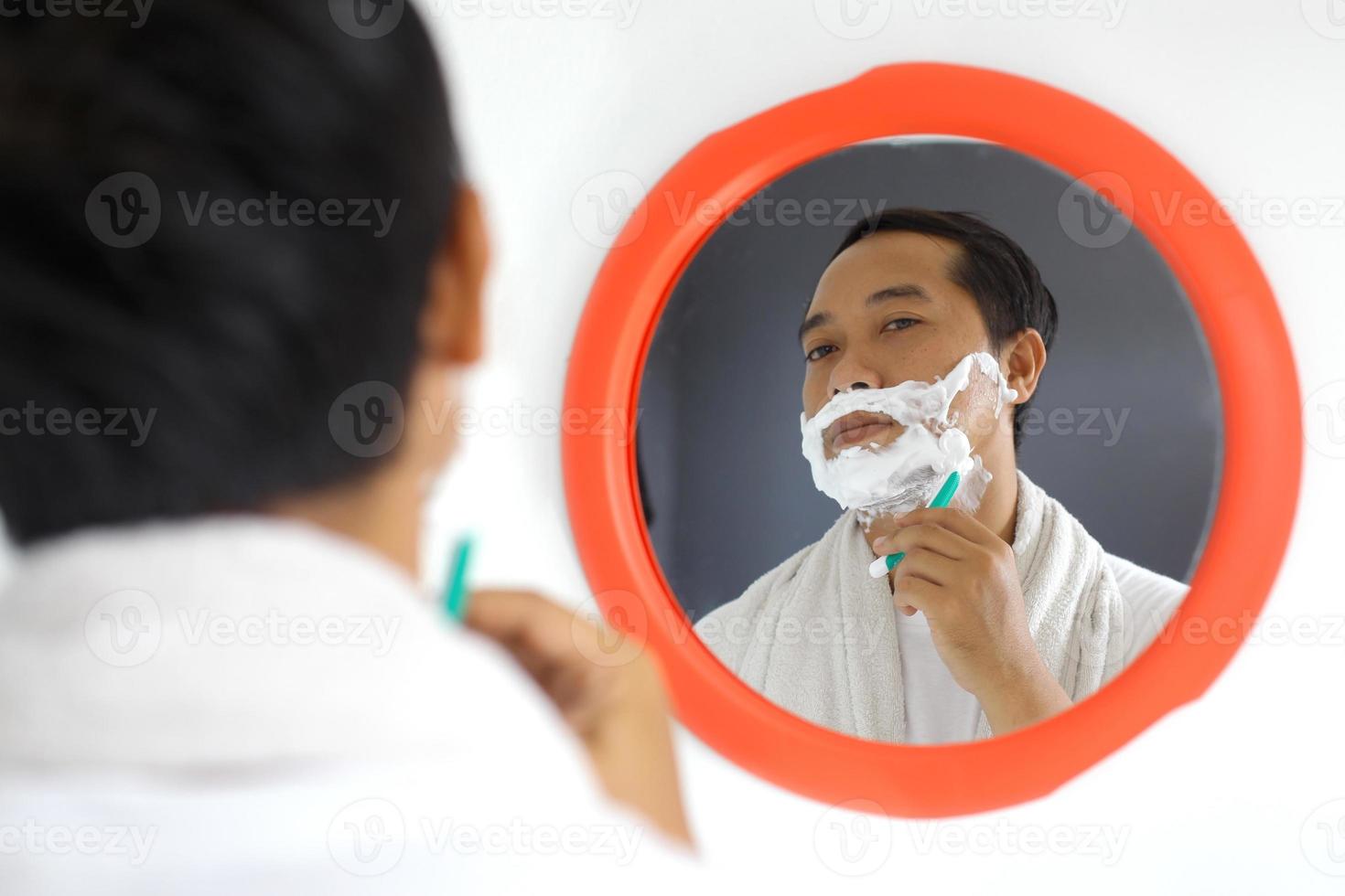 bel homme asiatique mûr se rasant devant le miroir photo