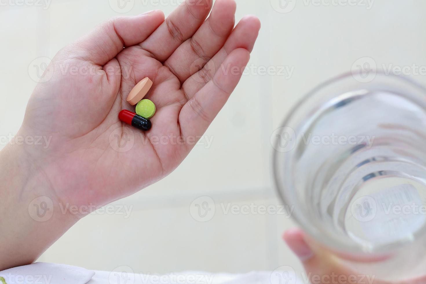 mains de femme tenant des pilules et un verre d'eau photo