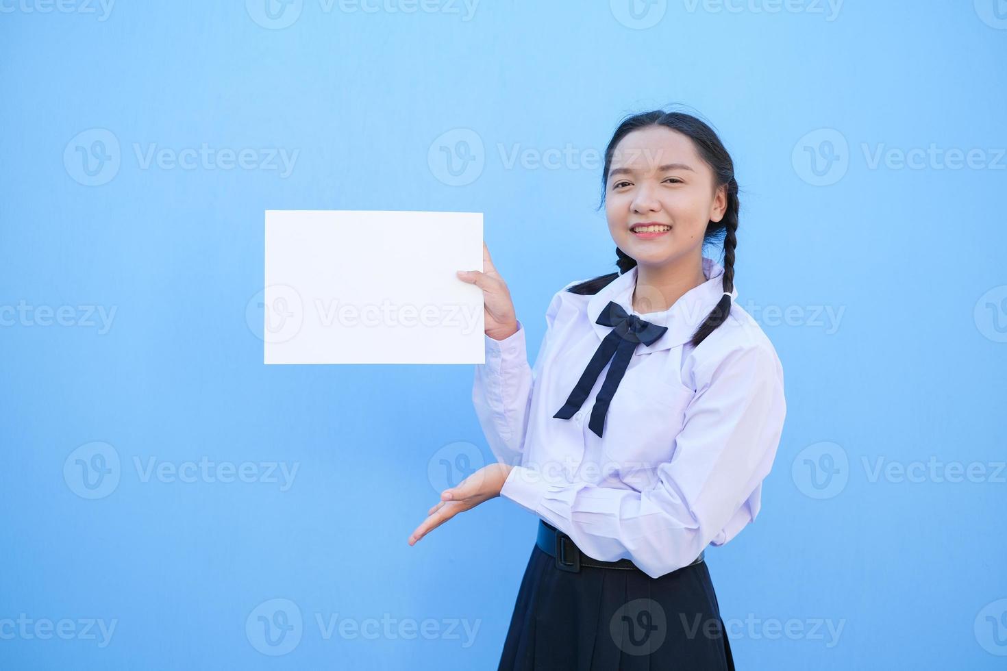 écolière tenant un panneau d'affichage sur fond bleu. photo