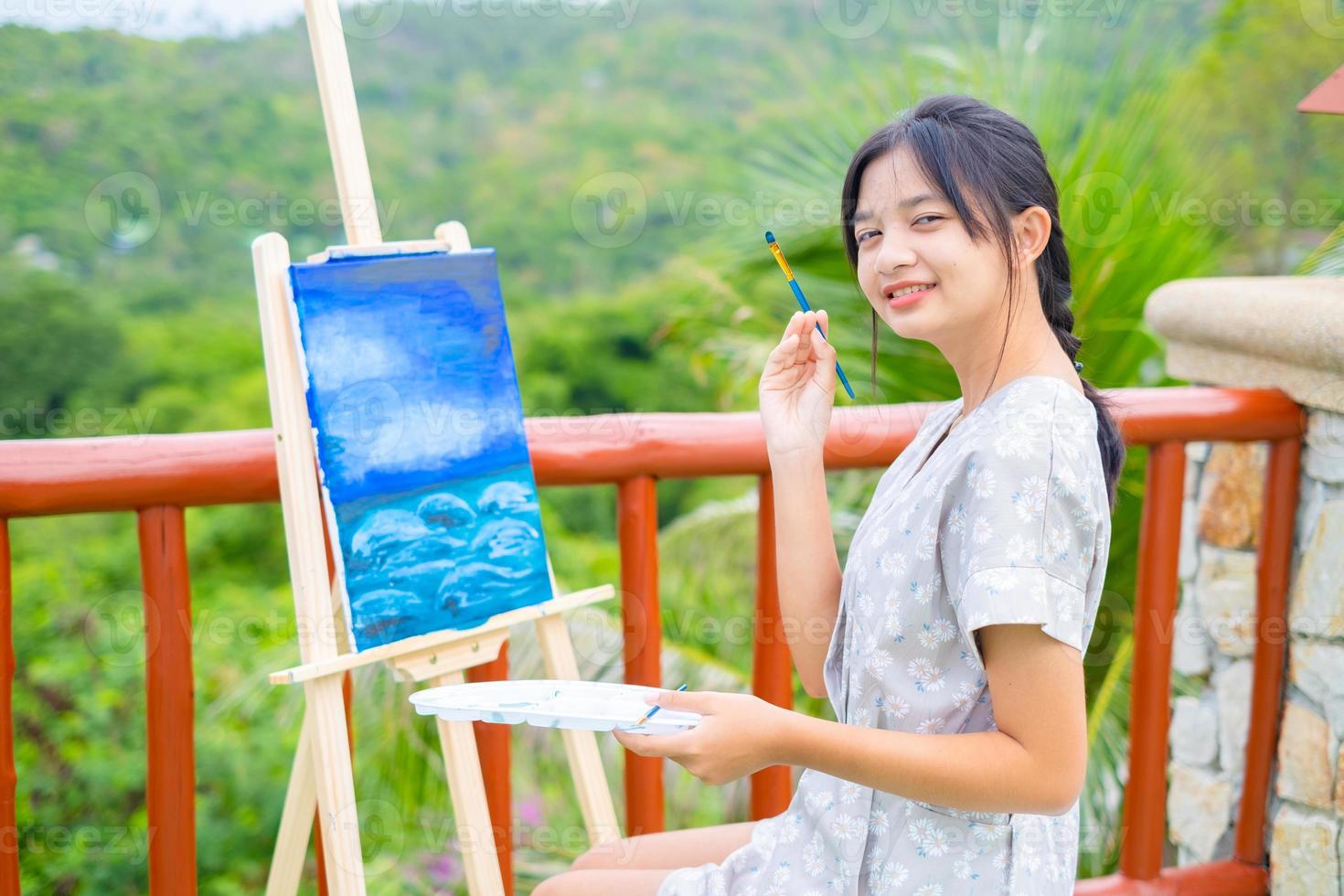 jeune fille à l'aide d'une image de dessin au pinceau sur papier de toile, à la belle vue sur le paysage à koh tao en thaïlande. photo