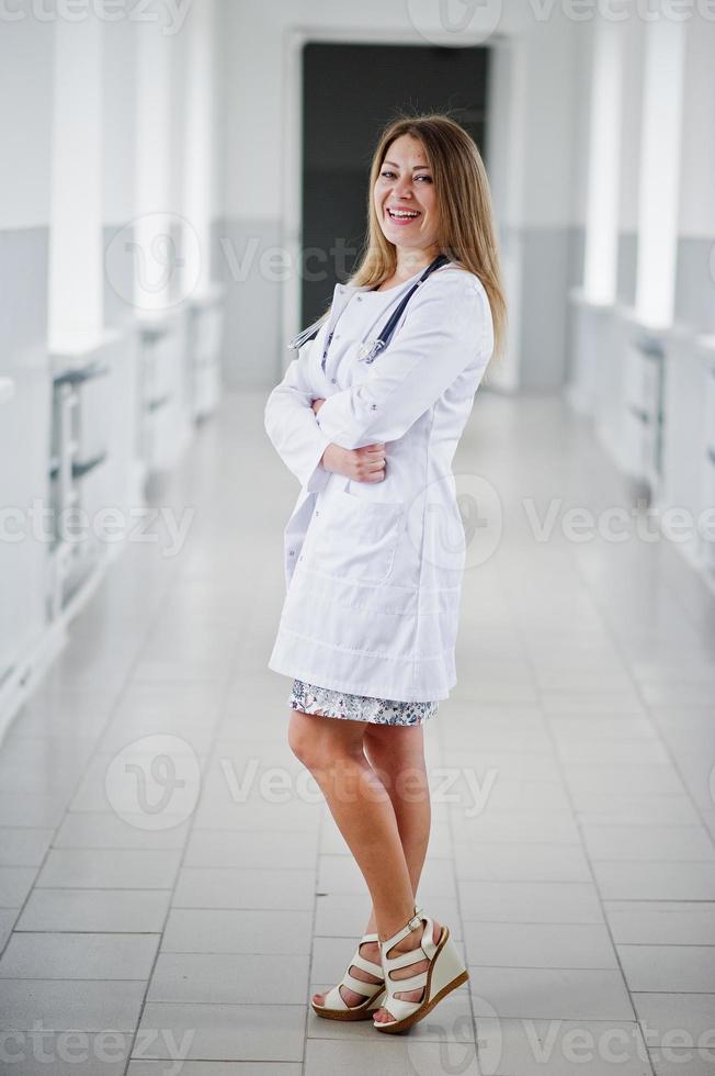 portrait d'un jeune médecin séduisant en blouse blanche avec stéthoscope posant à l'hôpital. photo