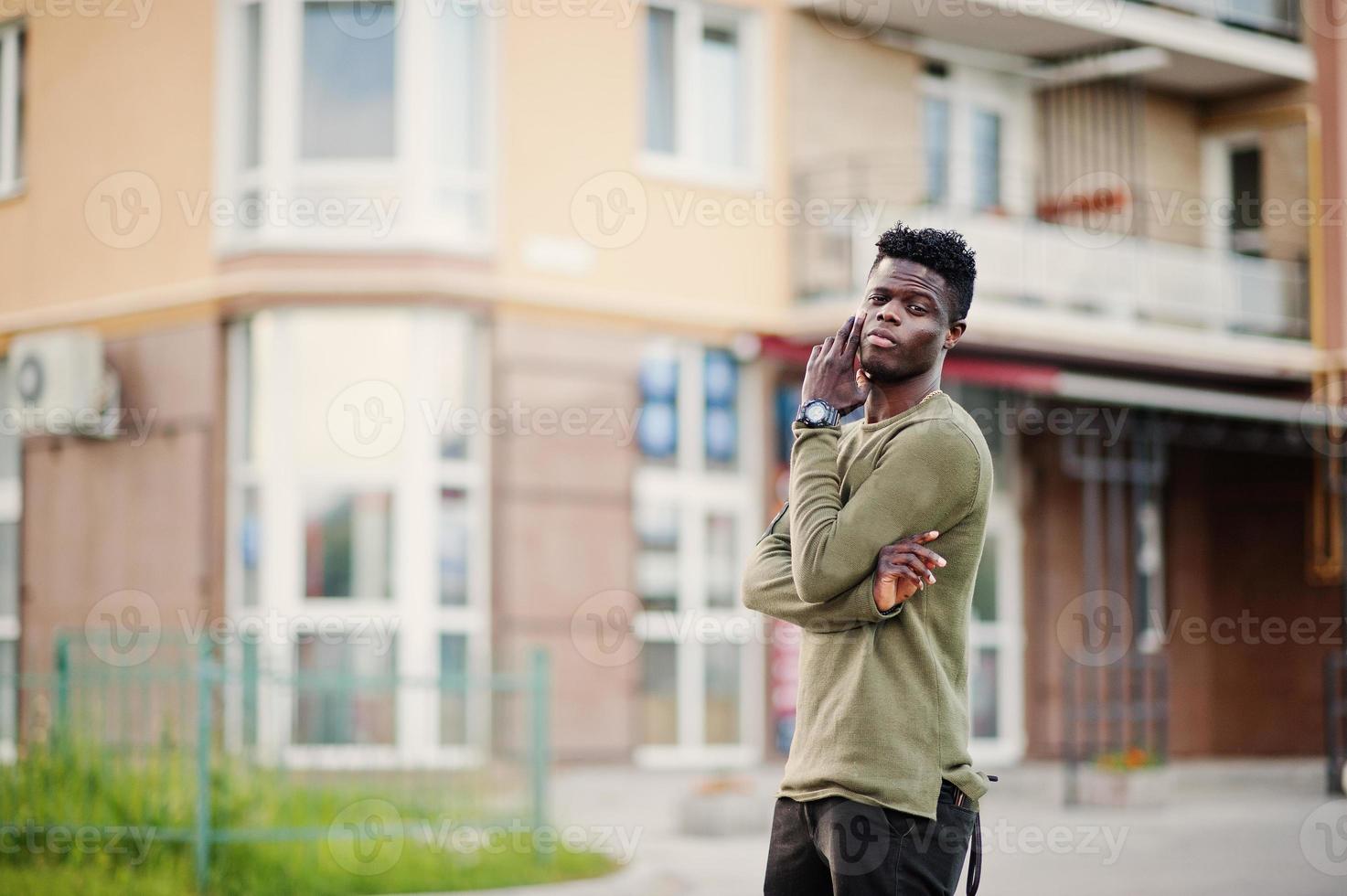 beau et séduisant homme afro-américain posant à côté du grand bâtiment dans une rue. photo