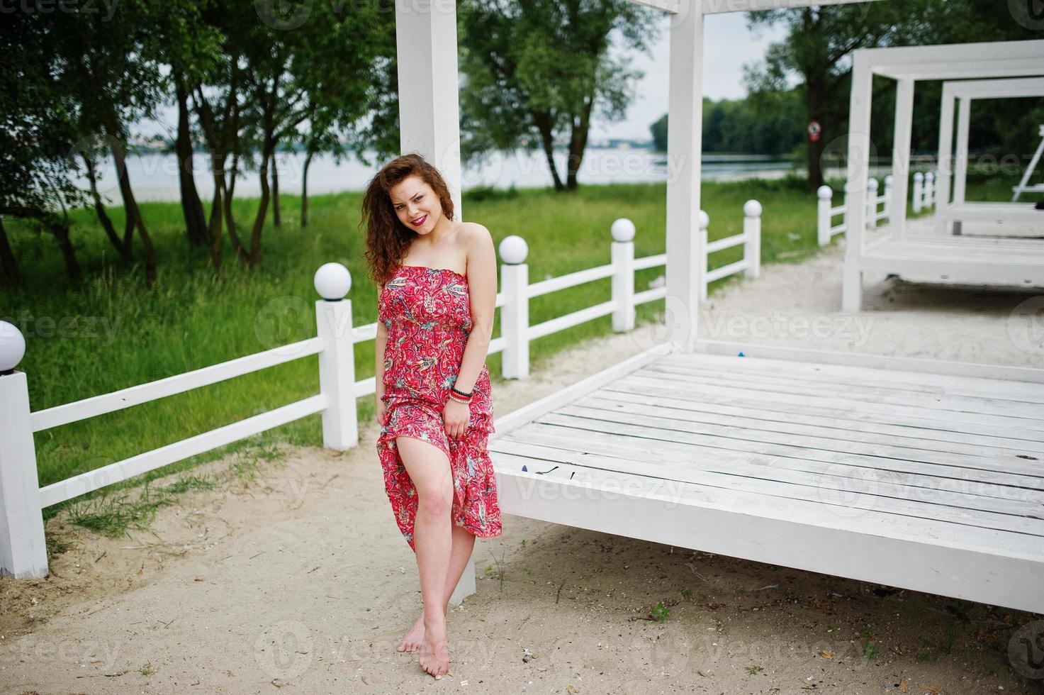 portrait d'une fabuleuse jeune fille vêtue d'une tenue chic posant sur une terrasse en bois blanc. photo