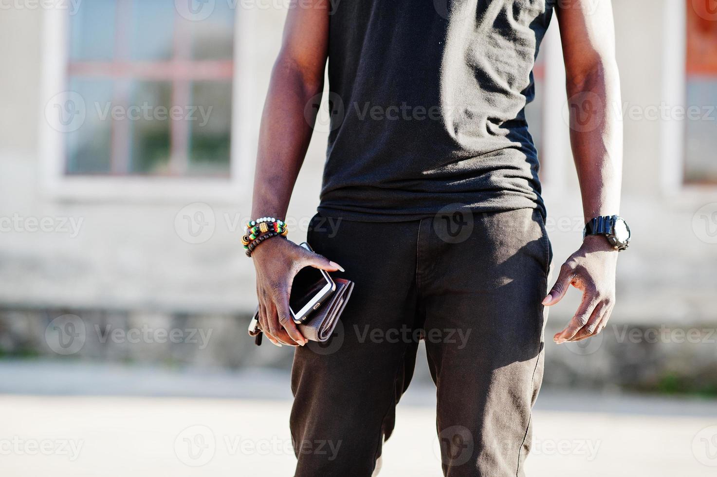 portrait d'un beau mec afro-américain en chemise musculaire noire posant dans une zone industrielle. photo