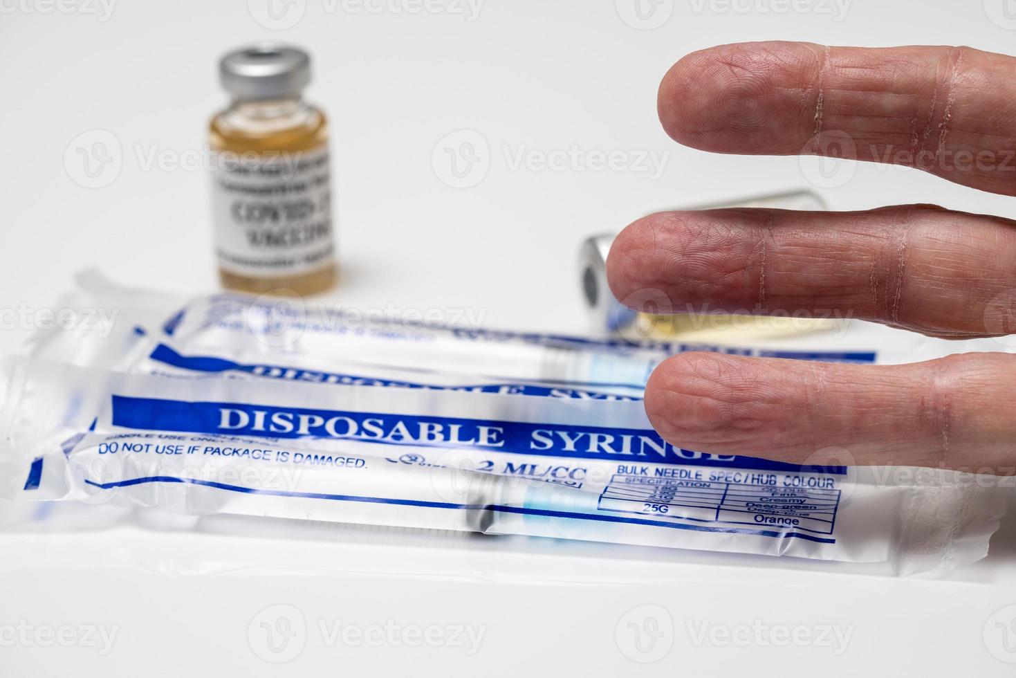 concept de dose de rappel covid-19 ou d'injection à l'aide de trois doigts au-dessus de seringues jetables emballées photo