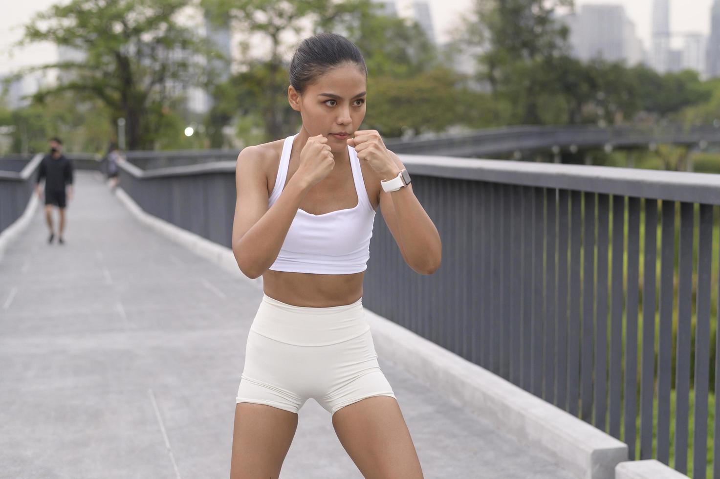 jeune femme de remise en forme en boxe de vêtements de sport dans le parc de la ville, saines et modes de vie. photo