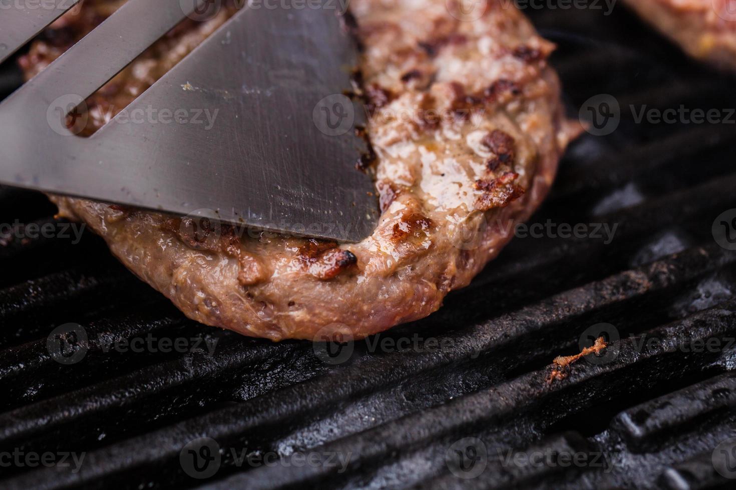 Burger de bœuf haché grillé sur une spatule contre un barbecue photo