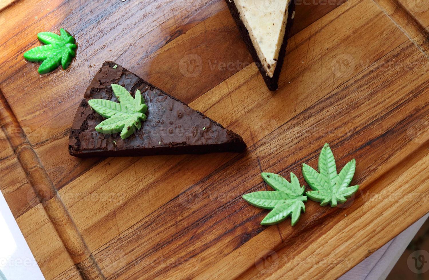 brownie en forme de triangle brun foncé sur plaque de bois brun, mélange d'ingrédients feuilles de cannabis, thaïlande. photo