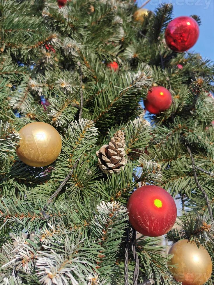 branches d'un sapin de noël vert et moelleux, décoré d'une boule dorée. décor de rue du nouvel an. photo