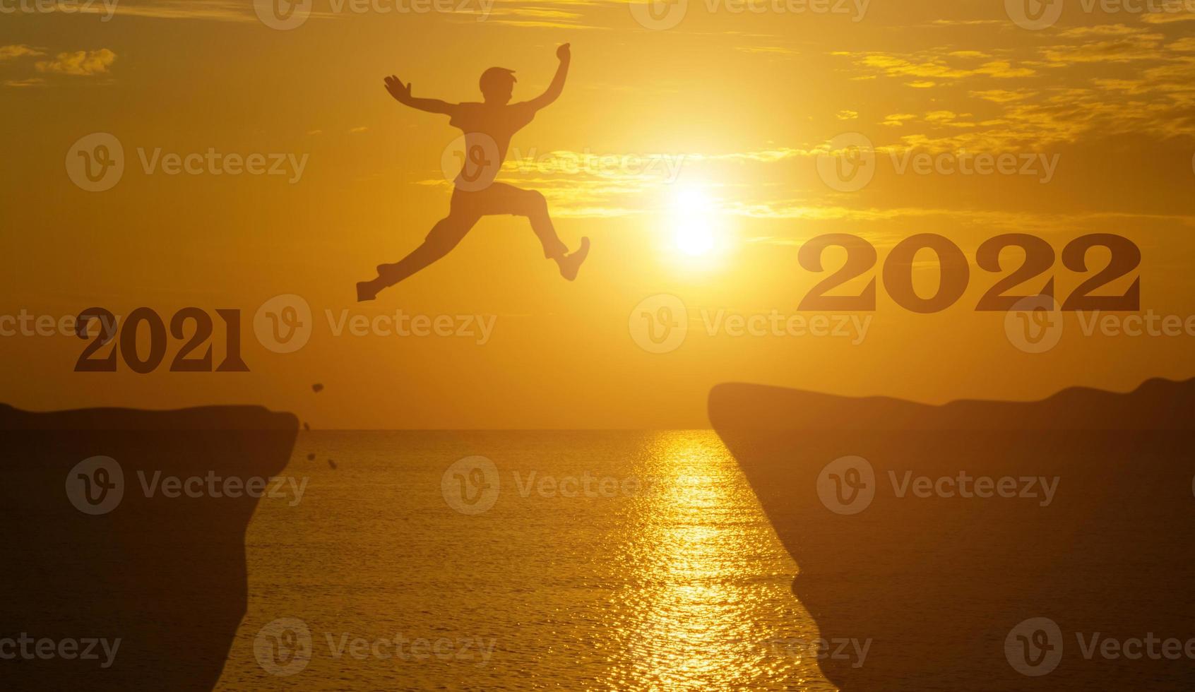 silhouette homme saute entre 2021 et 2022 ans avec fond de coucher de soleil. photo