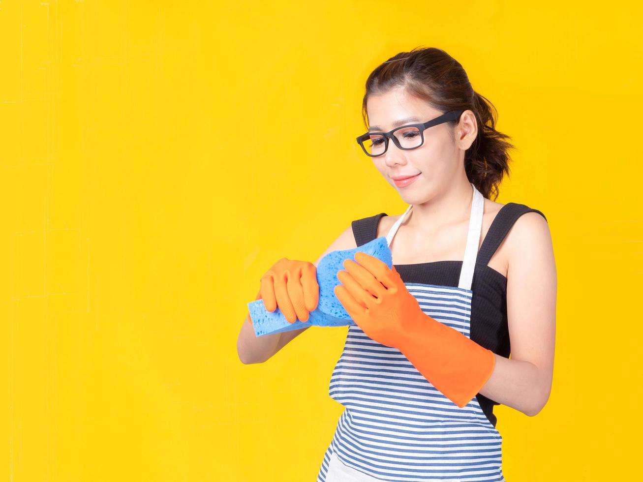 belle femme asiatique tenant une éponge pour nettoyer l'appareil et souriant joyeusement pour nettoyer la maison photo